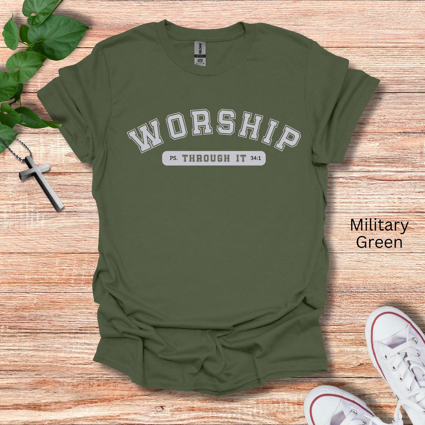 A military green t-shirt with the word Worship in college font with Through It written below siting Psalms 34:1.