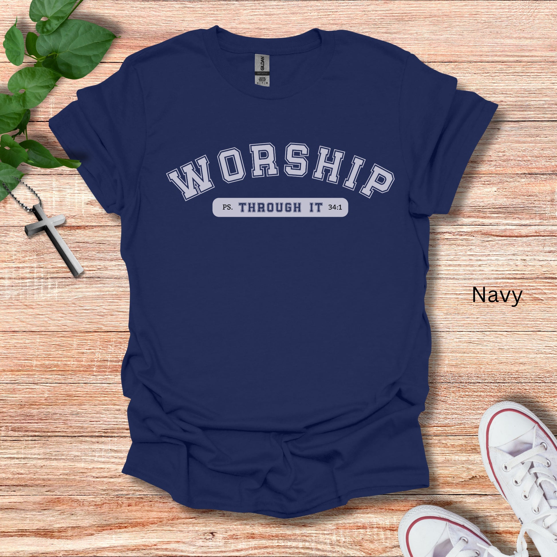 A navy blue t-shirt with the word Worship in college font and Through It written below siting Psalms 34:1.