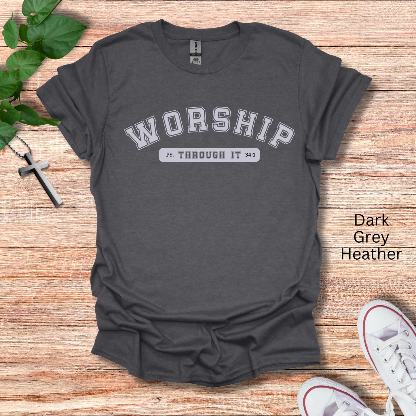 A dark heather t-shirt with the word Worship in college font with Through It written below siting Psalms 34:1.