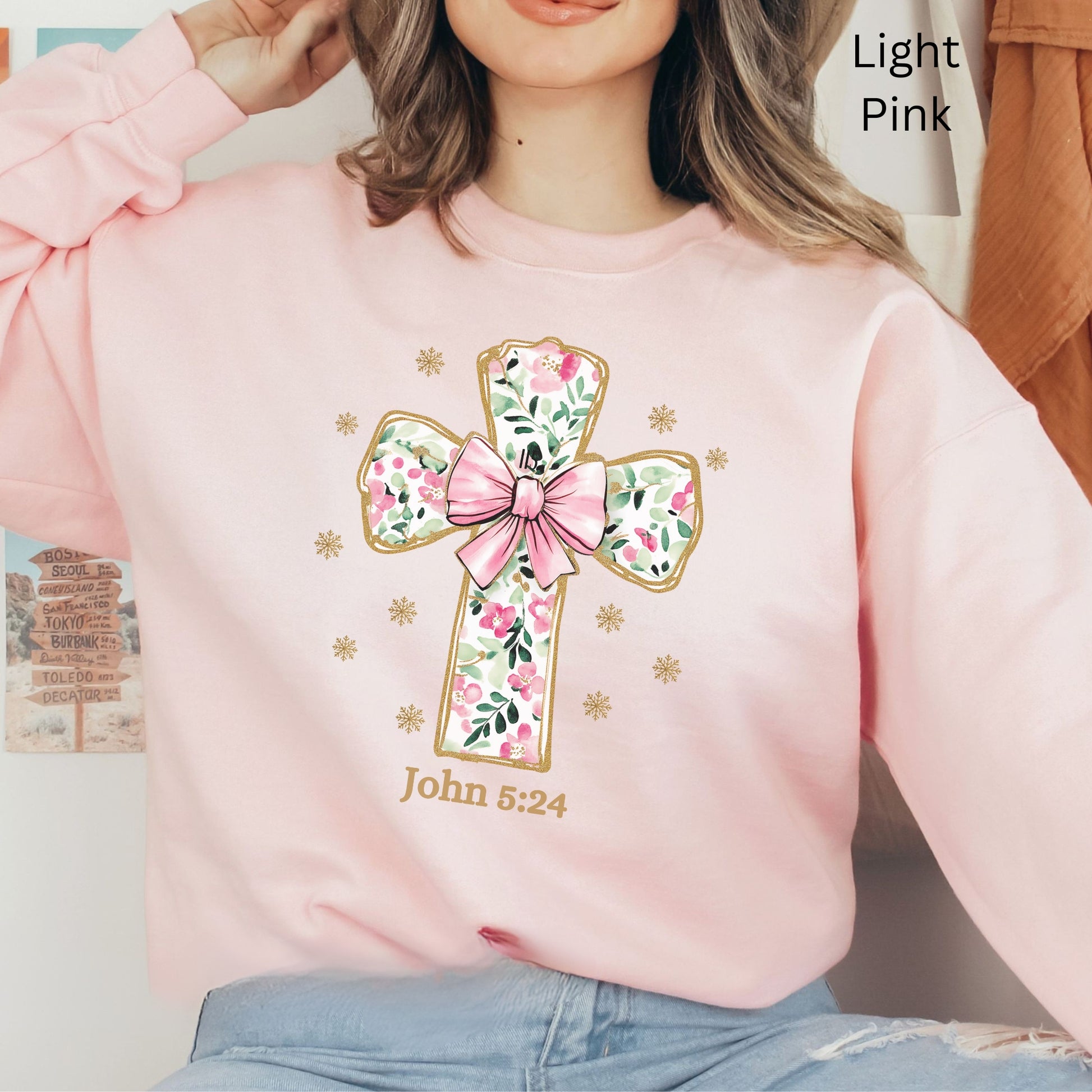 a beautiful flowered Cross with a pink coquette bow outlined in gold on this sweatshirt for her. John 3:24 is noted below.