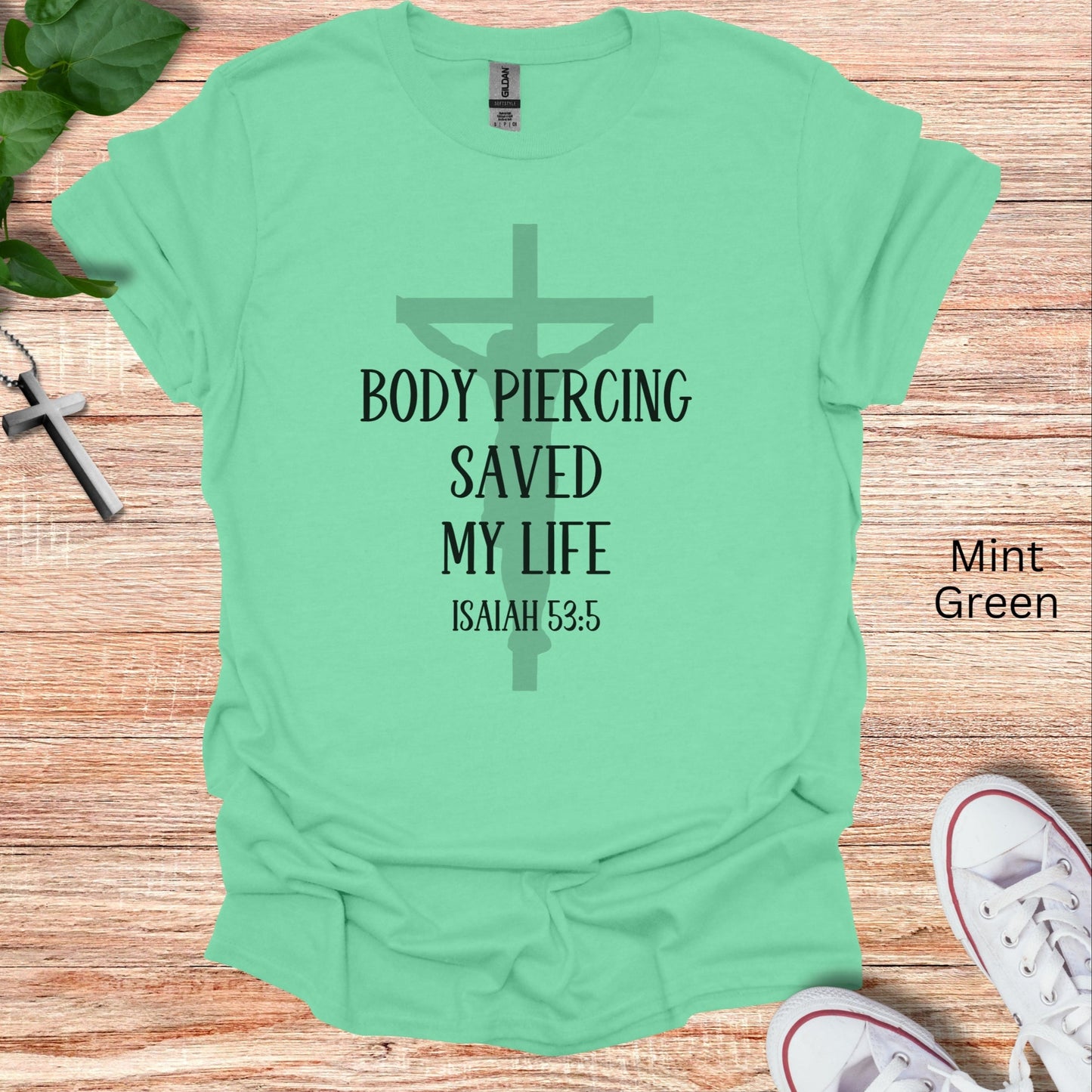 Body piercing saved my life graphic on this Christian t-shirt with a faded crucifix behind noting Isaiah 53:5